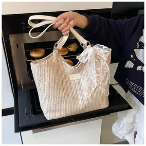Detail of hand-woven straw tote with white lace bow and cream leather handle