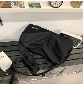 Macro di borsa a tracolla in nylon nero con logo MINGORILD appoggiata su una panchina