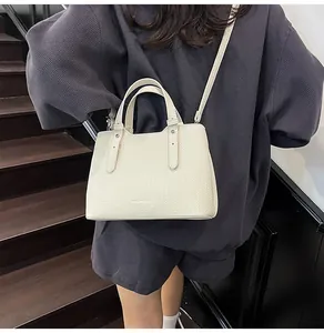 Borsa tote crema con trama intrecciata e doppi manici indossata da una modella