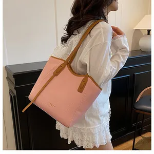 Close-up of pink woven tote bag with brown leather handles worn by a model