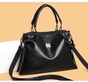 Detailed view of black oil-wax texture leather bag with brand logo and wide strap