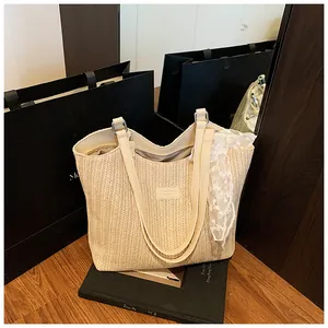 Close-up of woven straw tote bag featuring cream leather handles and lace scarf detail