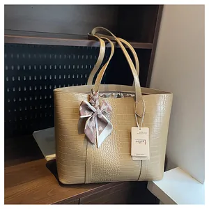 Détail du sac cabas kaki motif crocodile avec ruban à carreaux et étiquette de marque