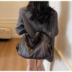Détail d'un grand sac cabas marron foncé avec fermetures éclair porté par un mannequin