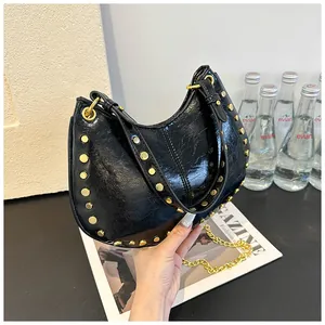 Détail du sac hobo noir en cuir verni brillant avec des rivets métalliques dorés