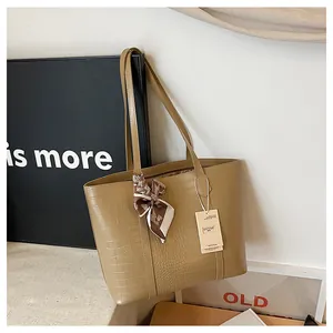 Détail du sac cabas kaki à motif crocodile avec foulard à carreaux et étiquette produit