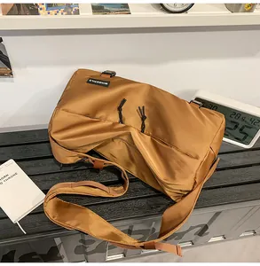 Dettaglio della borsa a tracolla in nylon caramello con coulisse nere e logo del marchio