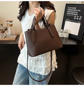 Dettaglio della borsa tote marrone scuro con trama intrecciata e rivetti in metallo argento