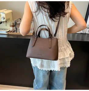 Dettaglio della borsa tote in pelle intrecciata marrone con manici e cinturini con rivetti
