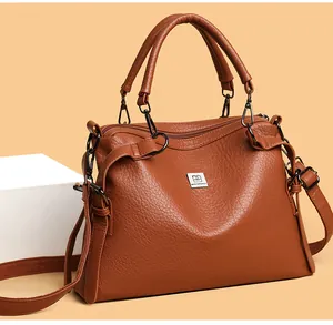 Detail of caramel brown pebbled leather tote bag with silver logo and wide shoulder strap