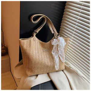 Detail of woven straw tote bag featuring a delicate white lace bow and leather strap