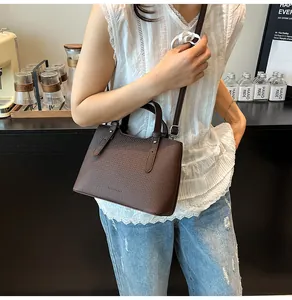 Dettaglio della borsa tote marrone scuro con trama intrecciata indossata da una modella