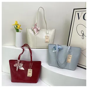 Détail des cabas motif crocodile en beige, bordeaux et bleu avec des foulards en soie