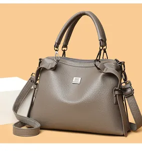 Detail view of the taupe leather tote bag with a wide adjustable shoulder strap and metal logo