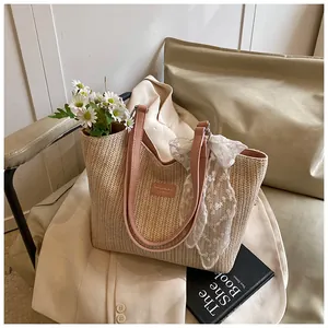 Close-up of beige woven tote bag with pink leather handles and delicate lace scarf