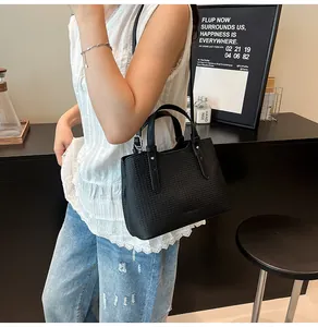 Dettaglio della trama intrecciata nera della borsa tote in un contesto di stile moderno