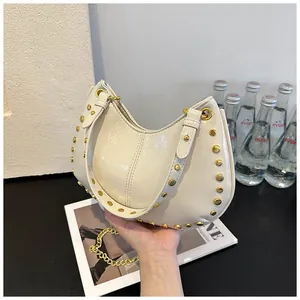 Détails du sac hobo crème avec clous dorés et grosse chaîne sur un magazine