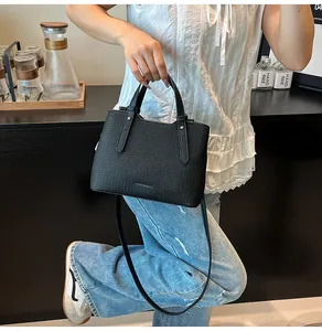 Dettaglio di una borsa a mano nera intrecciata con tracolla versatile e manici superiori