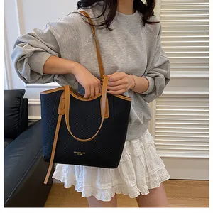 Detail of black textured tote bag with brown leather handles and fashion lettering
