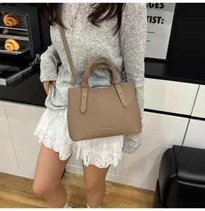 Dettaglio borsa tote in pelle intrecciata kaki con rivetti e tracolla indossata da modella