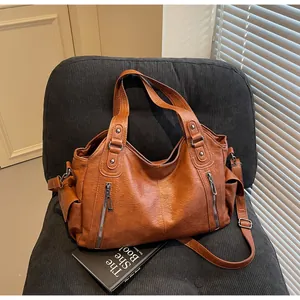 Détail du grand sac cabas en similicuir marron avec fermetures éclair sur fauteuil en velours