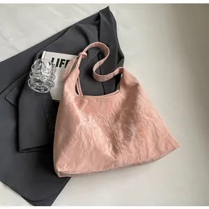 Détail du sac cabas rose clair avec texture cuir plissé sur fond de costume gris