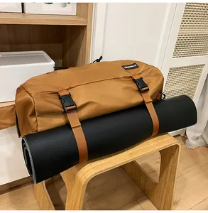 Dettaglio borsa fitness marrone con tappetino yoga nero fissato da cinghie a fibbia