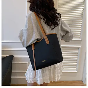 Detail of contrast stitching and gold logo on a large black and brown tote bag