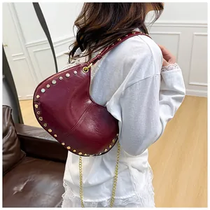 Détail du sac demi-lune bordeaux avec clous dorés et bandoulière chaîne métal
