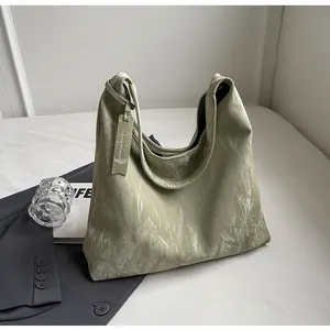 Détail du sac hobo vert clair avec texture en cuir marbré et étiquette suspendue