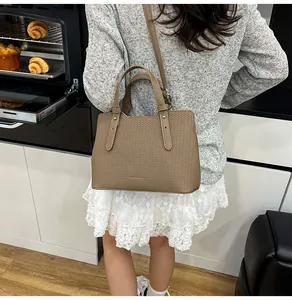 Dettaglio di una borsa tote kaki che mostra la superficie grainé e il design a due manici