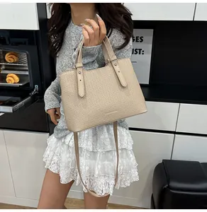 Dettaglio della borsa tote beige con trama intrecciata, doppi manici e fibbia in metallo