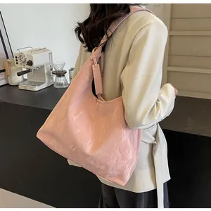 Grand sac cabas rose en cuir froissé porté par un mannequin dans un cadre de café épuré
