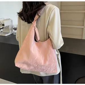 Détail du sac cabas rose pâle en tissu texturé avec bandoulière à nœud décoratif