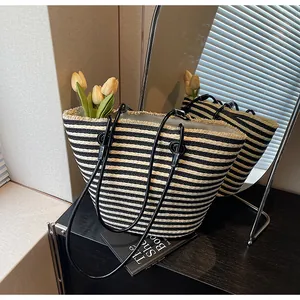 Detailed close-up of woven black and white striped tote bag with fringe edge and leather handles