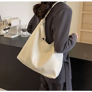 Détail du sac hobo en cuir PU crème avec étiquette latérale porté par un mannequin