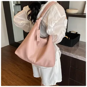 Sac hobo rose en cuir grainé porté par un mannequin dans un intérieur moderne et chic