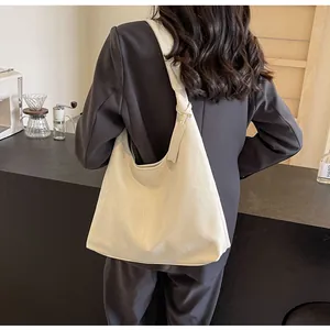 Gros plan d'un sac cabas en similicuir blanc cassé avec large bandoulière sur modèle