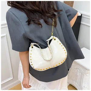 Vue détaillée du sac demi-lune blanc avec clous dorés et élégante bandoulière