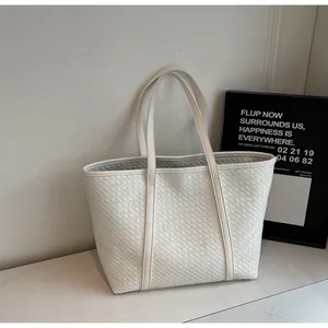 Detail of white woven tote bag showing premium intrecciato texture and slim shoulder straps