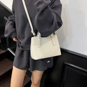 Borsa tote minimalista in pelle beige con rivetti argentati e tracolla regolabile