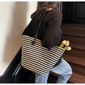 Close-up of woven tote bag with black and white stripes and tassel fringe details