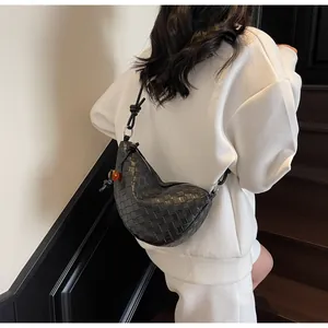 Detail of black woven leather crescent bag with shoulder knot and orange bead charm