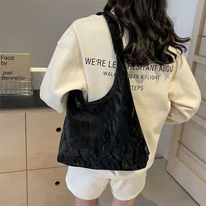Grand sac cabas noir plissé pour femme porté par un mannequin dans un intérieur cosy