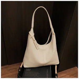 Gros plan du sac cabas en cuir grainé crème avec étiquette Cherrmate sur fond en bois