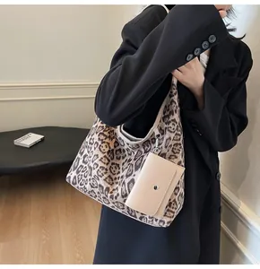Détail d'un sac cabas léopard avec mini pochette beige sur fond de blazer noir