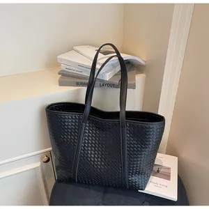 Detail of a large black woven leather tote bag with long shoulder straps for daily use
