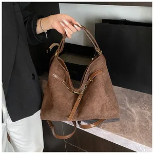 Close-up of brown suede tote bag with vintage metal buckle and leather handle