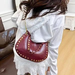 Sac croissant bordeaux style punk avec clous dorés et bandoulière chaîne porté à l'épaule