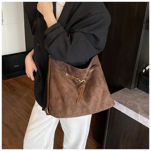 Close-up detail of dark brown suede tote bag with leather strap and metal buckle accent